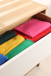 Chest of drawers with different folded clothes, closeup