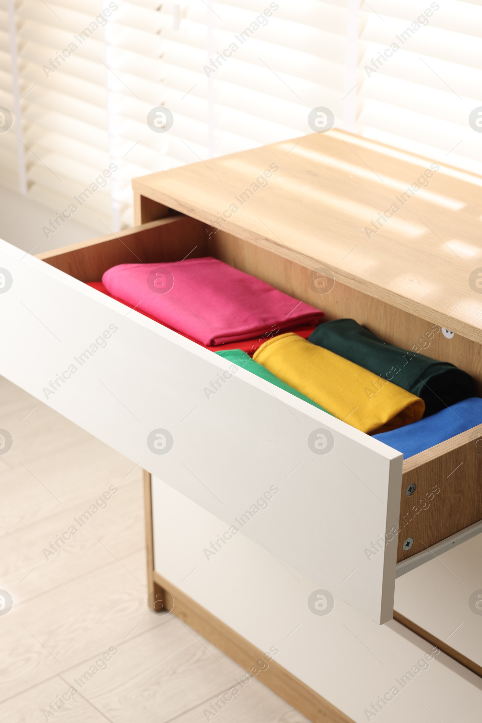 Photo of Chest of drawers with different folded clothes, closeup