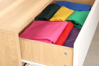 Chest of drawers with different folded clothes, closeup