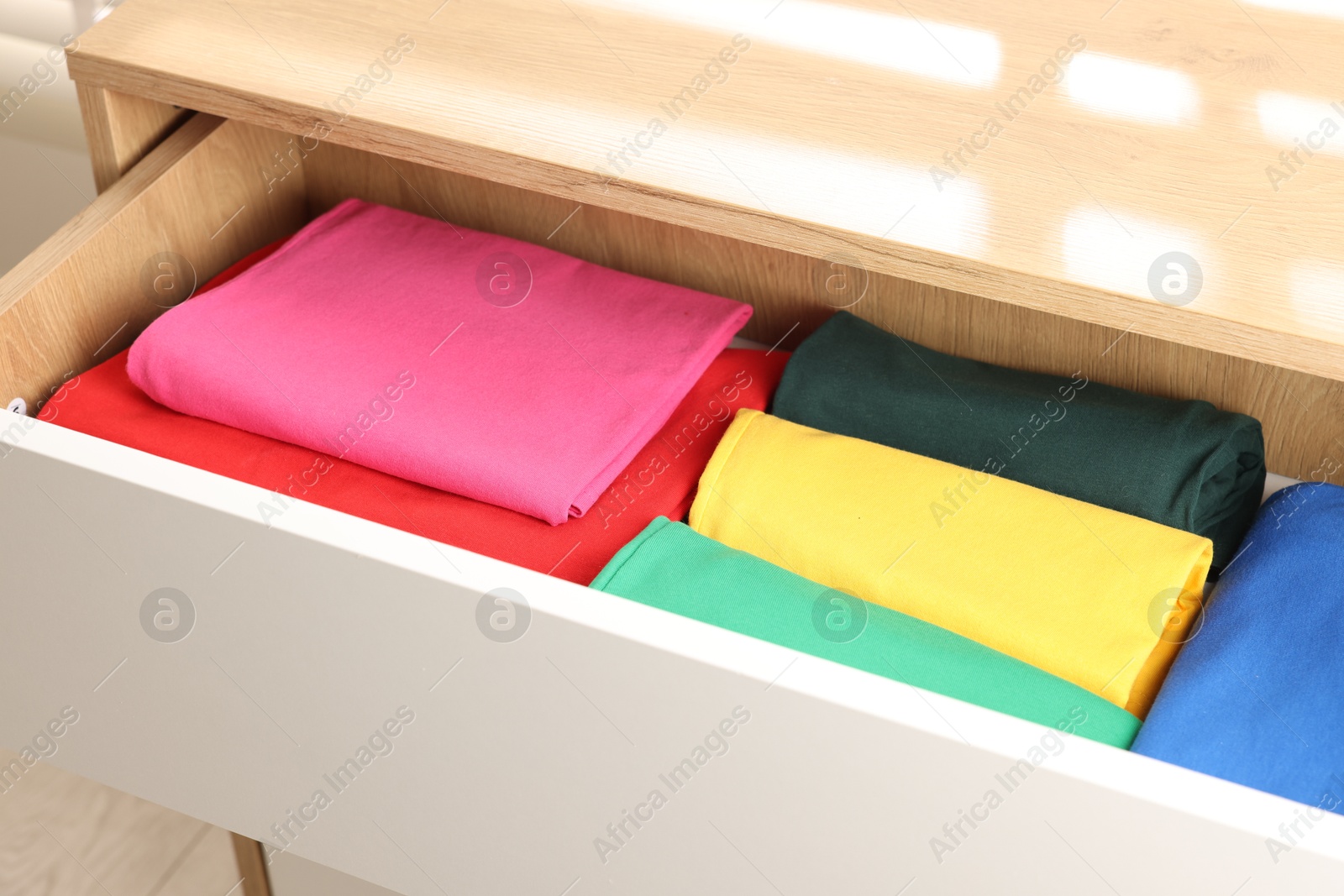 Photo of Chest of drawers with different folded clothes, closeup