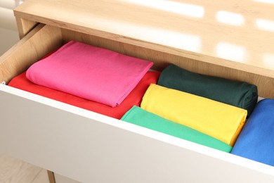 Photo of Chest of drawers with different folded clothes, closeup