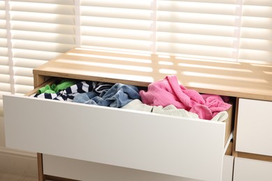 Photo of Cluttered chest of drawers indoors. Clothes in mess