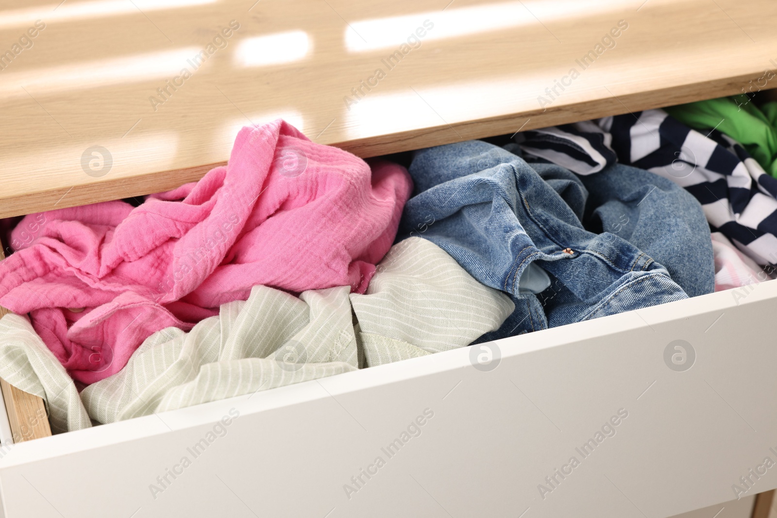 Photo of Cluttered chest of drawers indoors, closeup. Clothes in mess