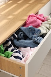 Photo of Cluttered chest of drawers indoors, closeup. Clothes in mess