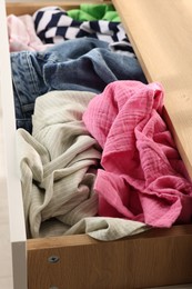 Cluttered chest of drawers indoors, closeup. Clothes in mess