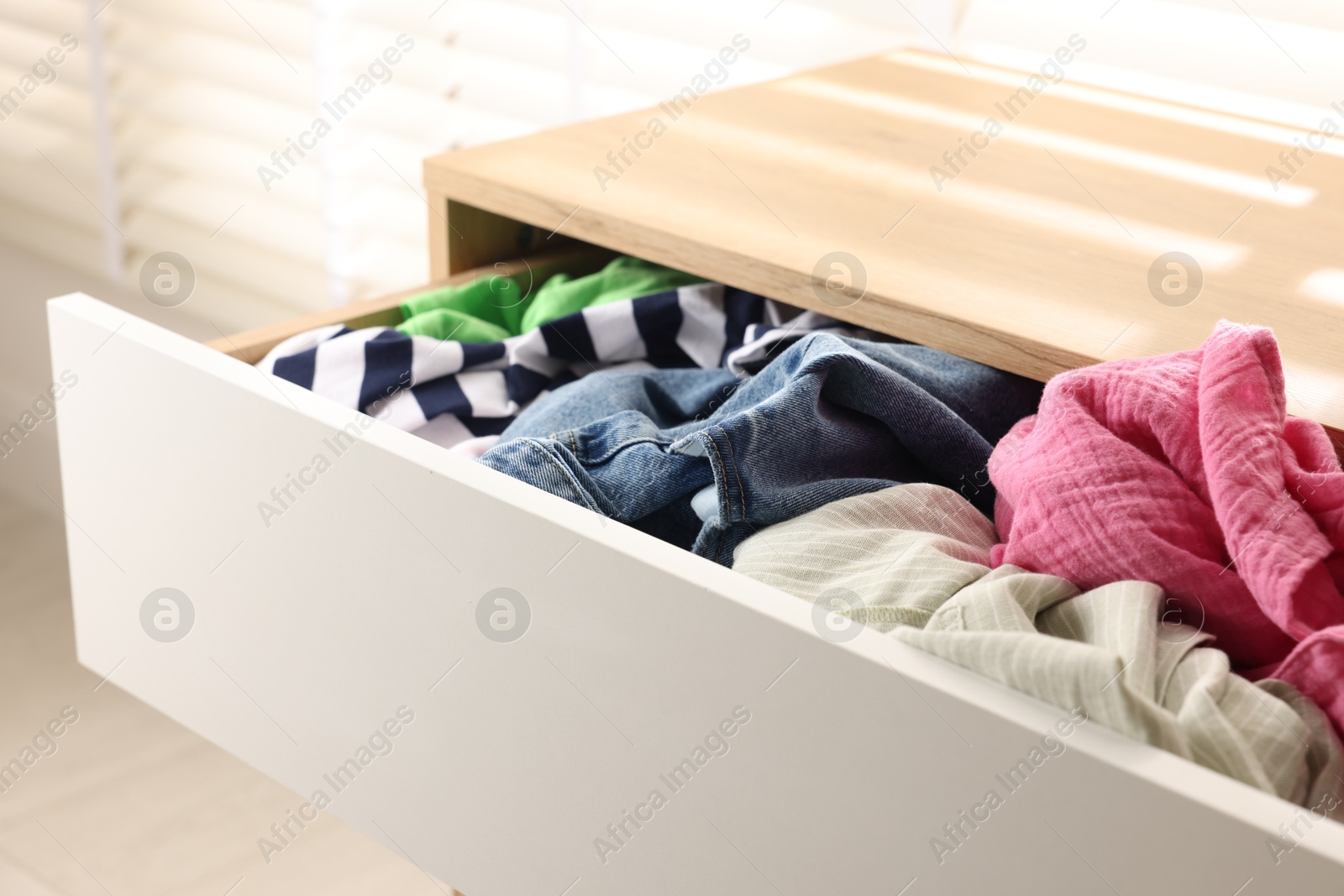 Photo of Cluttered chest of drawers indoors, closeup. Clothes in mess