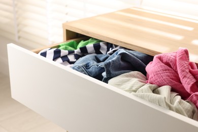 Photo of Cluttered chest of drawers indoors, closeup. Clothes in mess