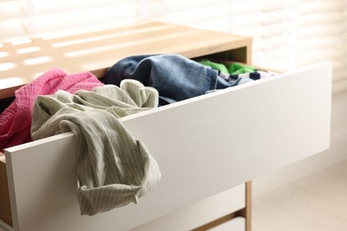 Cluttered chest of drawers indoors, closeup. Clothes in mess