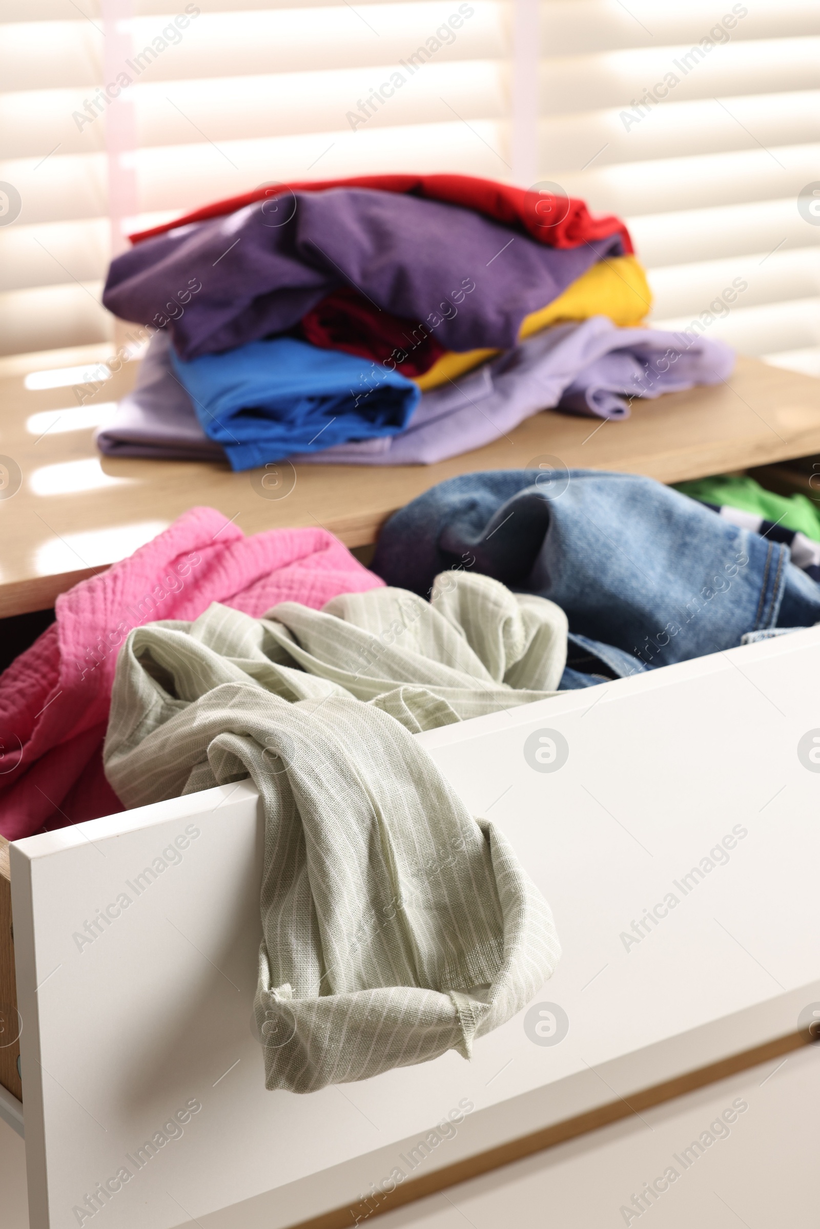 Photo of Cluttered chest of drawers indoors, closeup. Clothes in mess