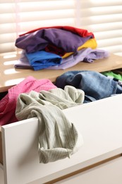 Cluttered chest of drawers indoors, closeup. Clothes in mess