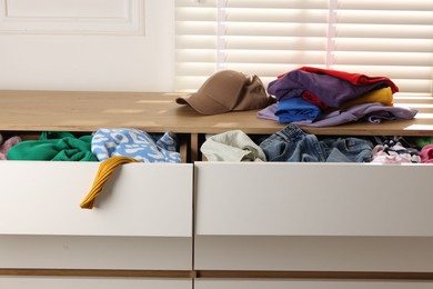 Cluttered chest of drawers indoors, closeup. Clothes in mess