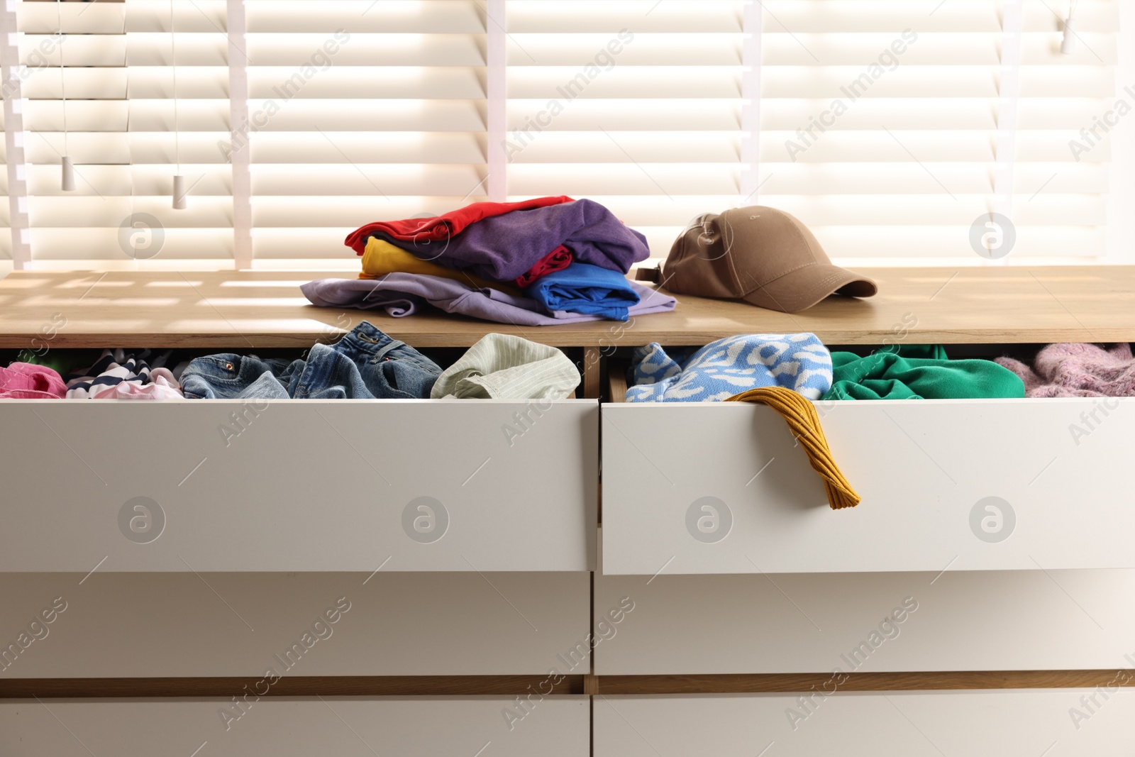 Photo of Cluttered chest of drawers indoors, closeup. Clothes in mess