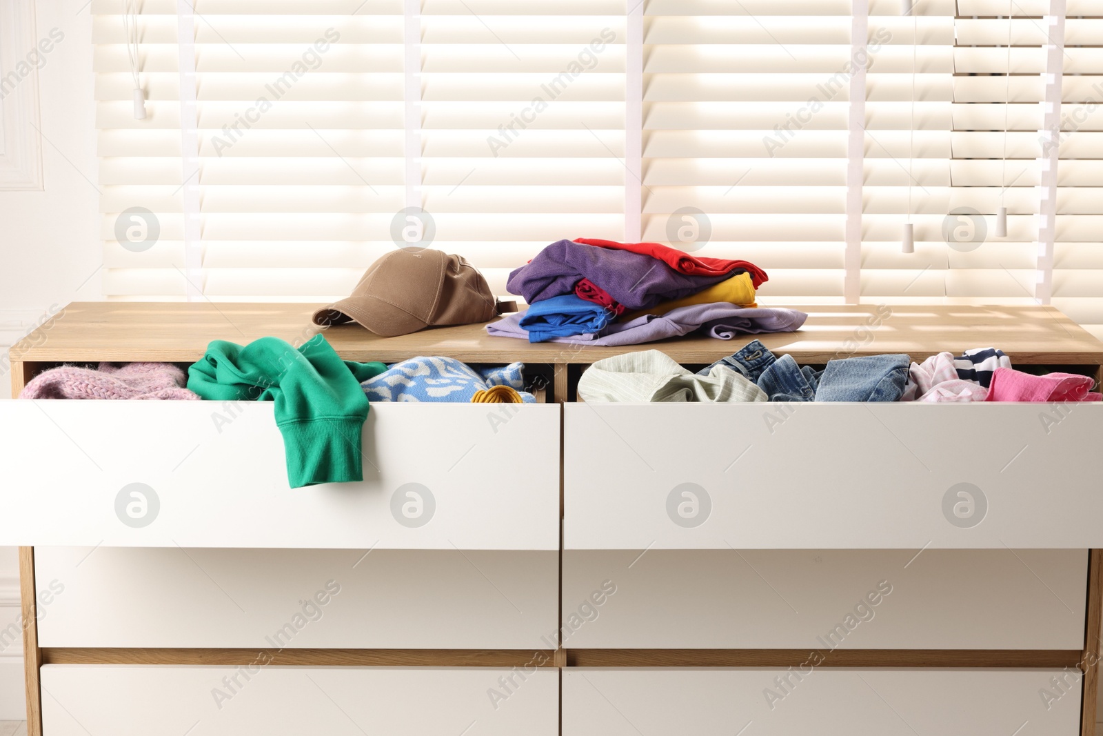 Photo of Cluttered chest of drawers indoors, closeup. Clothes in mess