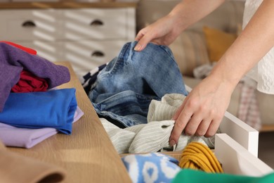 Photo of Woman organizing clothes in chest of drawers indoors, closeup