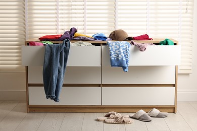 Photo of Cluttered chest of drawers indoors. Clothes in mess