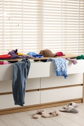 Cluttered chest of drawers indoors. Clothes in mess