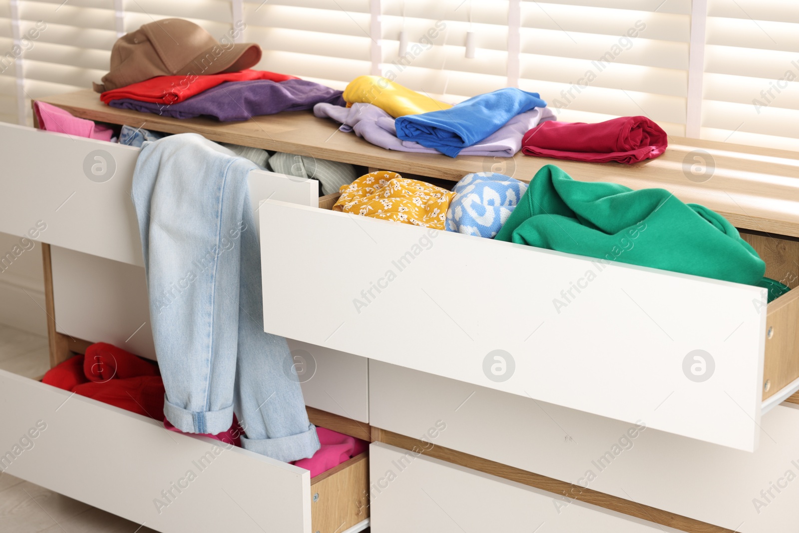 Photo of Cluttered chest of drawers indoors, closeup. Clothes in mess