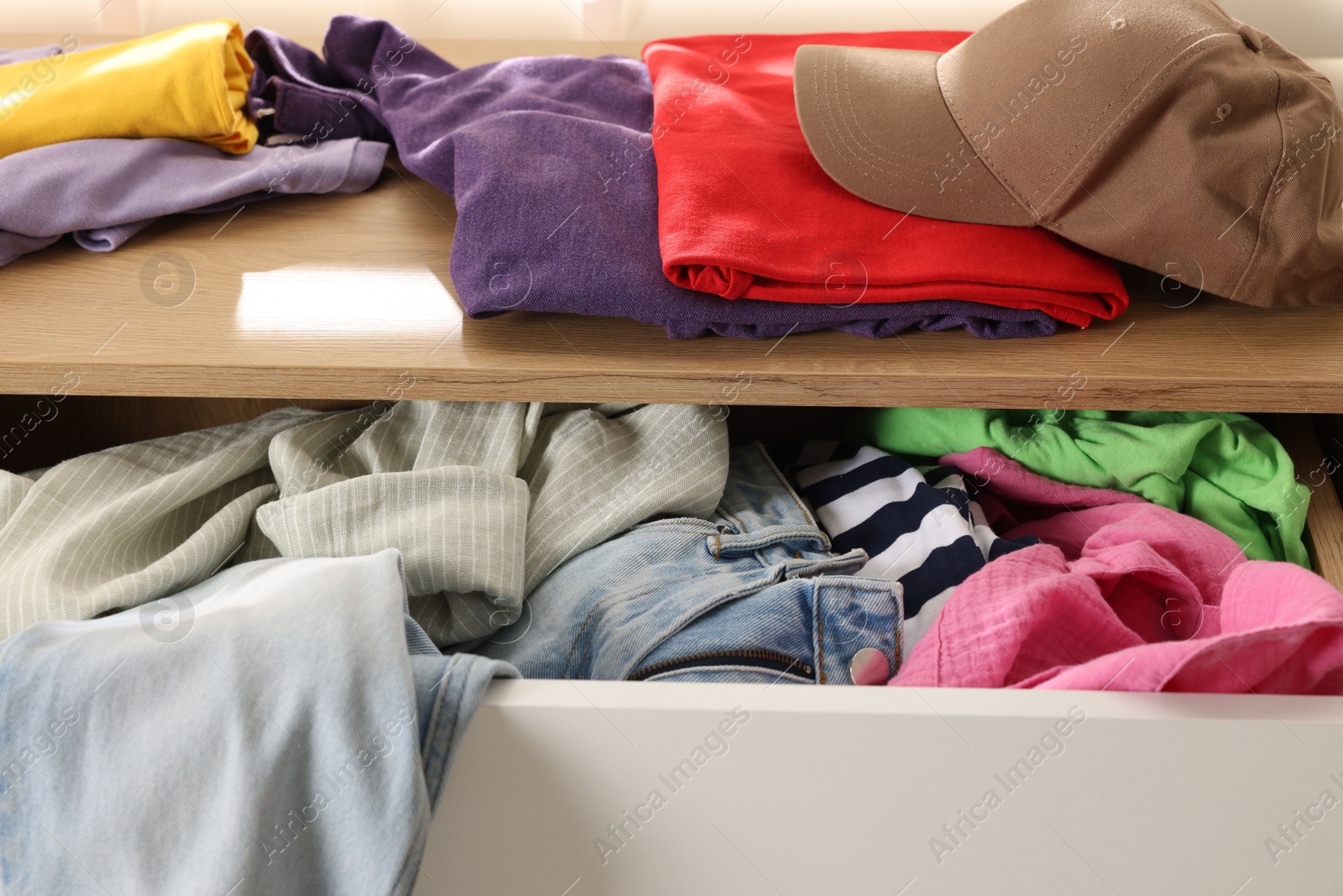 Photo of Cluttered chest of drawers indoors, closeup. Clothes in mess