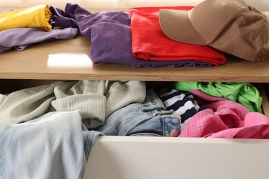 Cluttered chest of drawers indoors, closeup. Clothes in mess