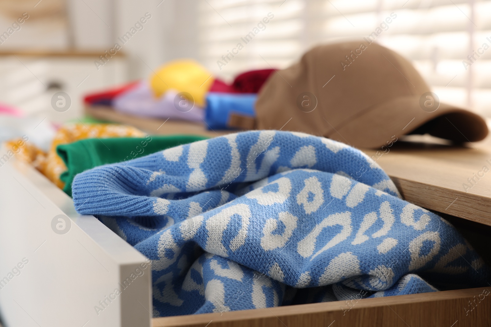 Photo of Cluttered chest of drawers indoors, closeup. Clothes in mess