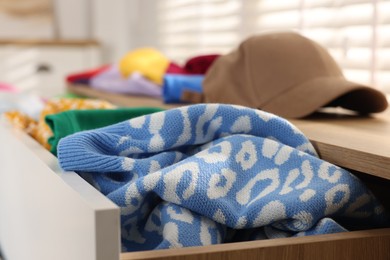 Cluttered chest of drawers indoors, closeup. Clothes in mess