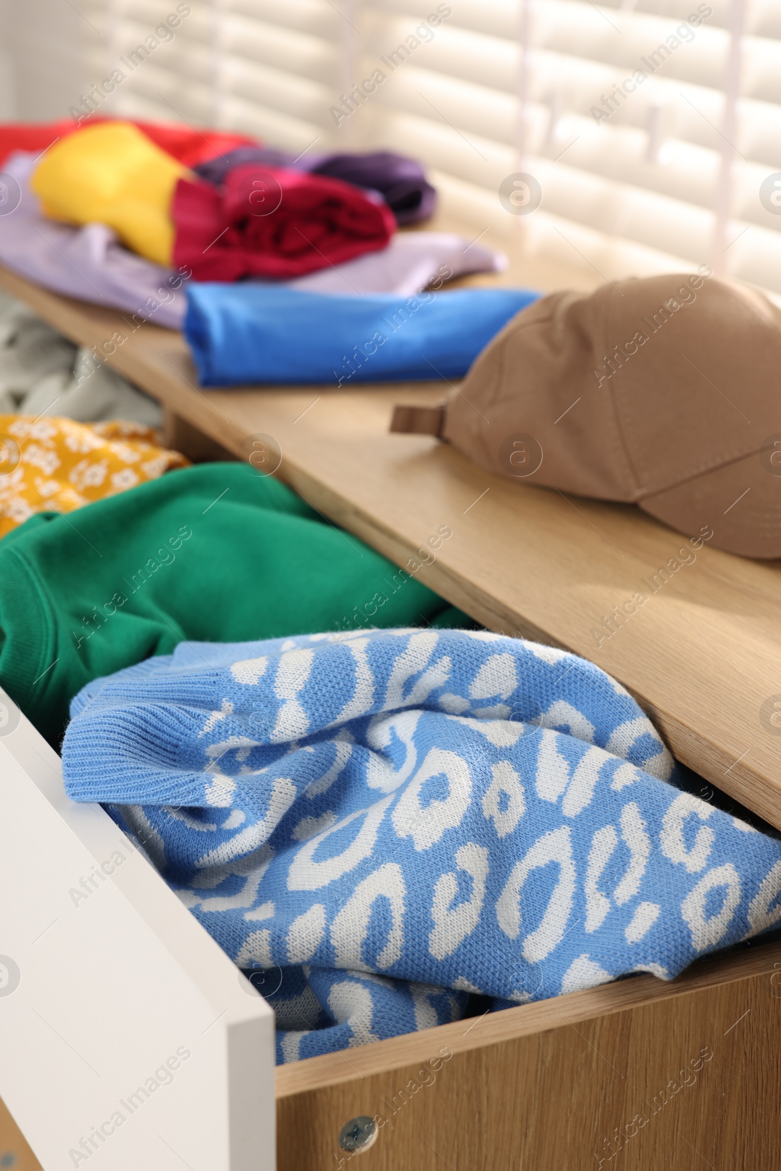 Photo of Cluttered chest of drawers indoors, closeup. Clothes in mess