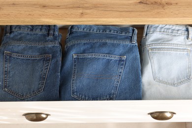 Chest of drawers with different folded jeans, above view