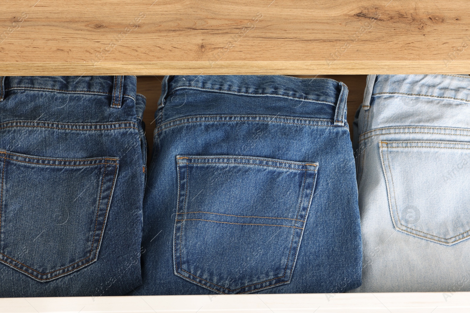 Photo of Chest of drawers with different folded jeans, above view