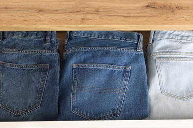 Chest of drawers with different folded jeans, above view