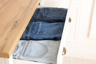 Chest of drawers with different folded jeans, closeup