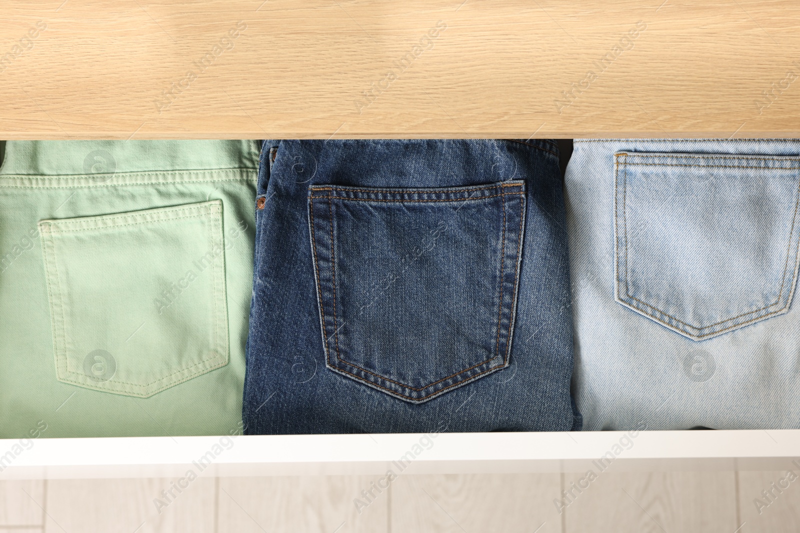 Photo of Chest of drawers with different folded jeans, above view