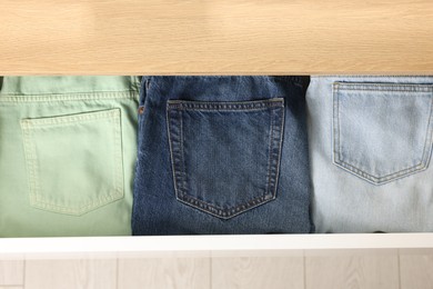 Chest of drawers with different folded jeans, above view