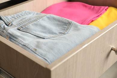 Chest of drawers with different folded clothes, closeup