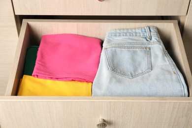 Chest of drawers with different folded clothes, closeup