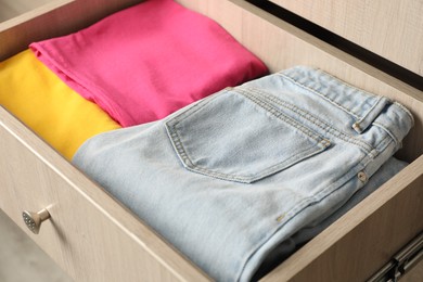 Chest of drawers with different folded clothes, closeup