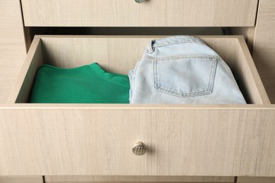 Chest of drawers with different folded clothes, closeup