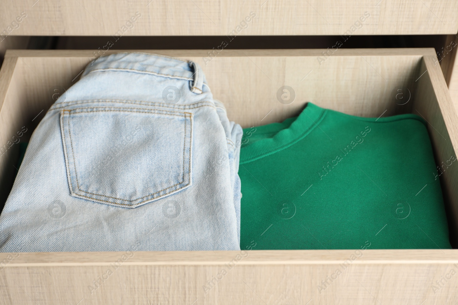 Photo of Chest of drawers with different folded clothes, closeup