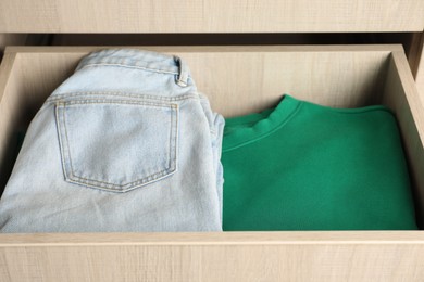 Photo of Chest of drawers with different folded clothes, closeup