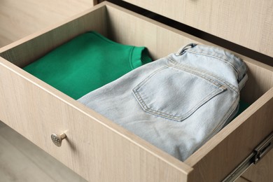 Photo of Chest of drawers with different folded clothes, closeup