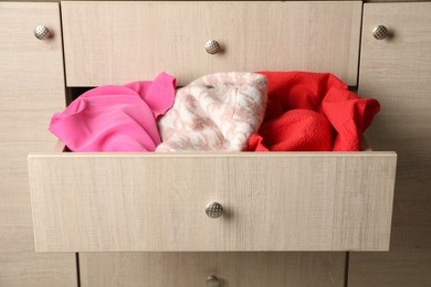 Chest of drawers with different folded clothes, closeup