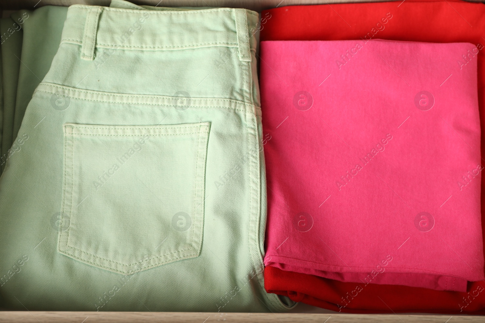 Photo of Chest of drawers with different folded clothes, closeup