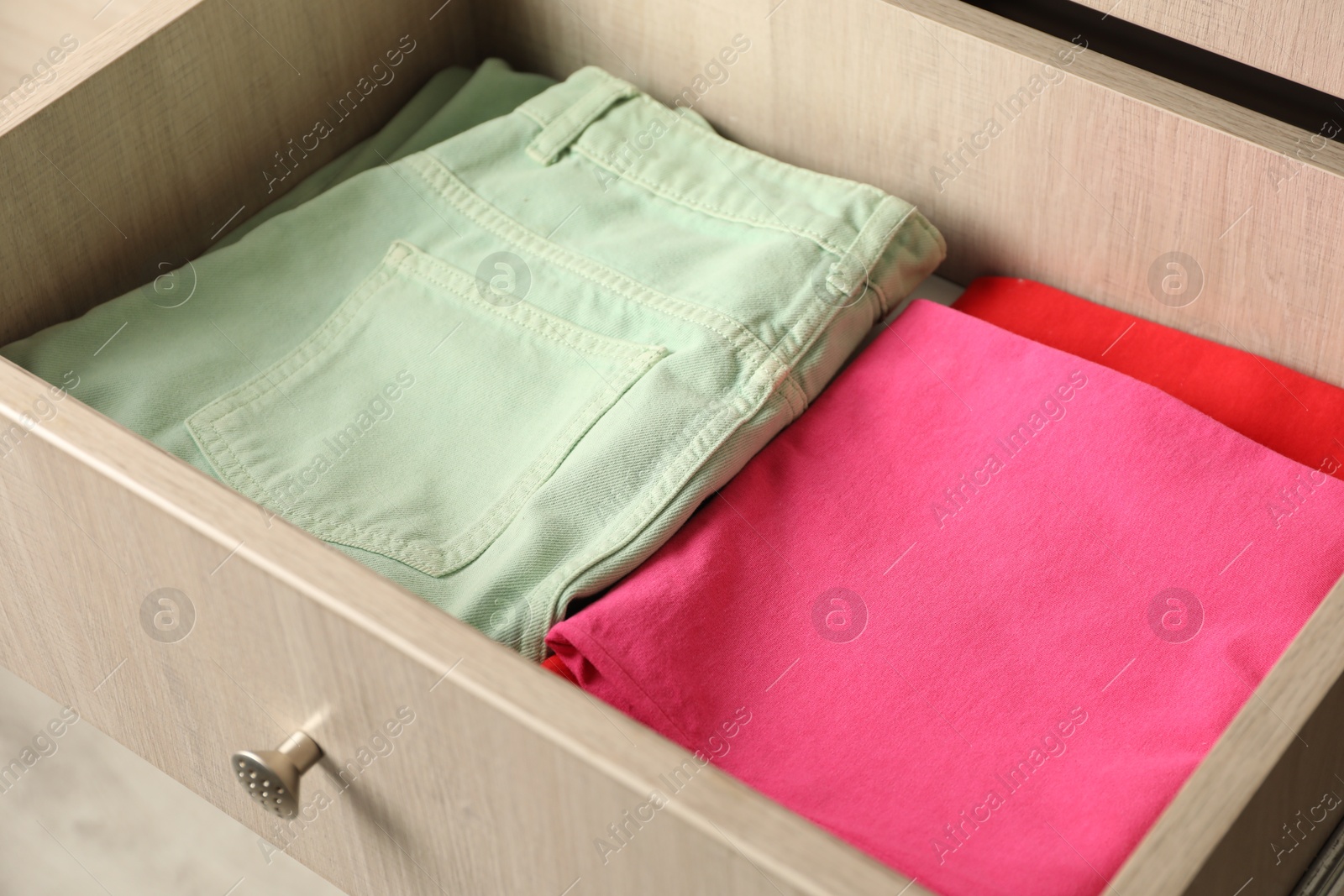 Photo of Chest of drawers with different folded clothes, closeup