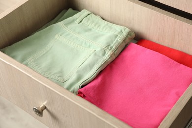 Chest of drawers with different folded clothes, closeup