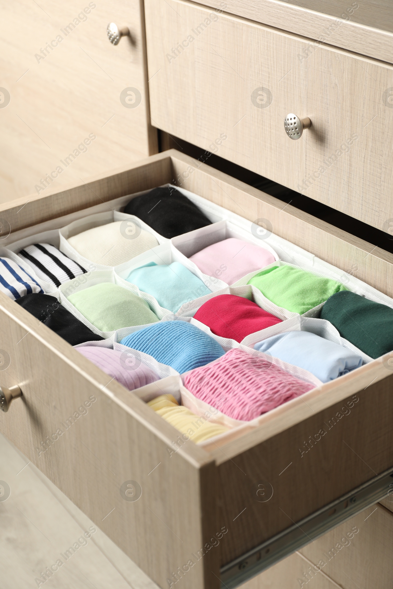 Photo of Chest of drawers with different folded clothes, closeup