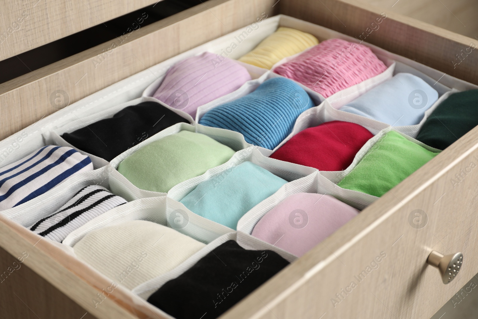 Photo of Chest of drawers with different folded clothes, closeup