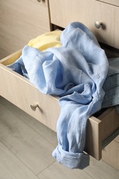 Photo of Cluttered chest of drawers, closeup. Clothes in mess