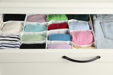 Chest of drawers with different folded clothes, closeup