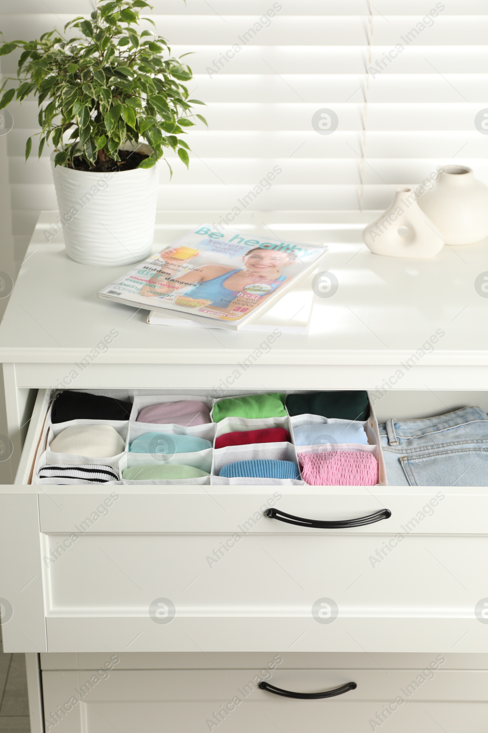 Photo of Chest of drawers with different folded clothes indoors