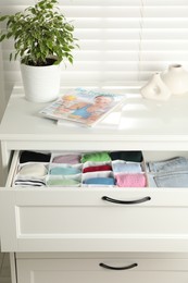 Chest of drawers with different folded clothes indoors