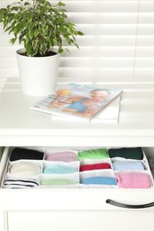 Photo of Chest of drawers with different folded clothes indoors